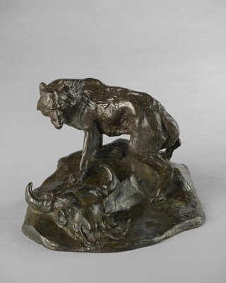 A bronze sculpture of a wolf standing over a bison skull with a rattlesnake hiding inside.