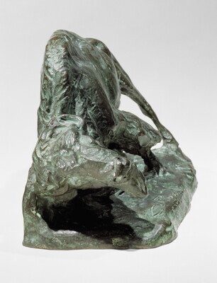 A bronze sculpture of a bison with his head and front leg lowered toward the ground.