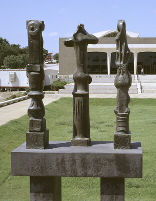 Three tall, vertical, bronze sculptures of organic forms atop a geometrically carved base.