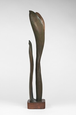 A wood sculpture of a tall, thin leaf with two smaller leaves on either side.