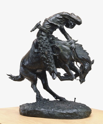 A sculpture of a man riding a bucking horse around a rattlesnake.