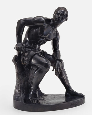 A bronze sculpture of a muscled Black man with manacles on his wrists leaning forward as he sits on a tree stump.