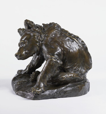 A bronze sculpture of a bear sitting on its haunches to clean itself with a hind leg.