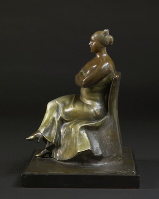 A bronze sculpture of a woman wearing an evening gown sitting with her legs and arms crossed.