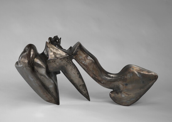 An abstract welded steel sculpture; its organic form has three "legs" that it rests on.