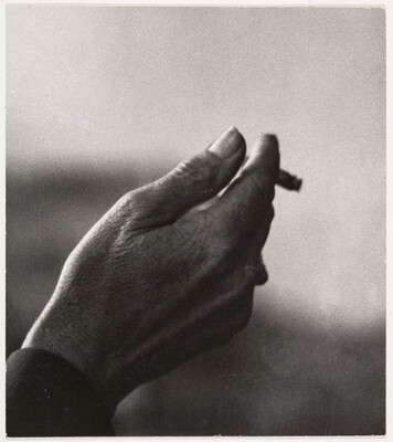 A black-and-white close-up photograph of a right hand holding an almost-finished cigarette.