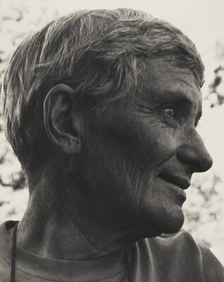 A black-and-white photograph of a smiling White woman, head turned in profile, with short hair and some wrinkles.