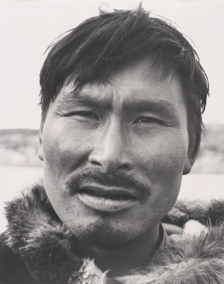A black-and-white photograph of a close-up of an Indigenous man with a mustache wearing fur at his neck.
