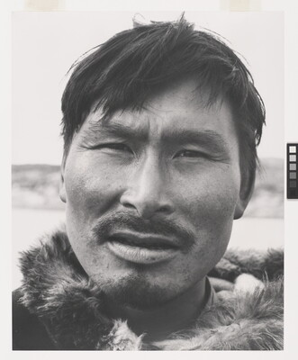 A black-and-white photograph of a close-up of an Indigenous man with a mustache wearing fur at his neck.