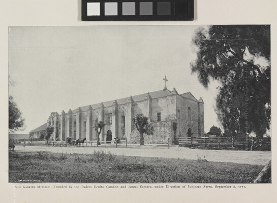 A black-and-white photograph of a mission church by a dirt road.