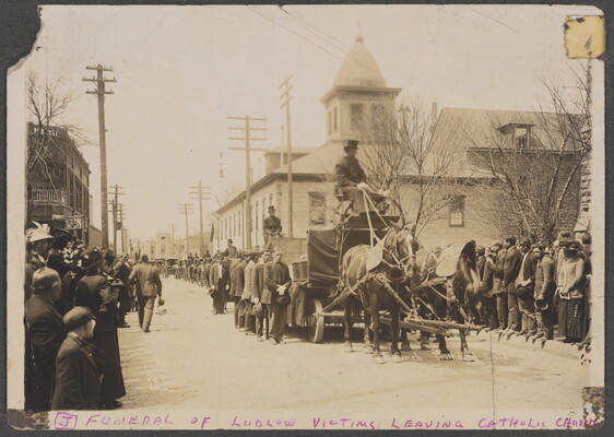 A sepia-toned photograph of crowds lining a street watching a horse-drawn funeral procession.