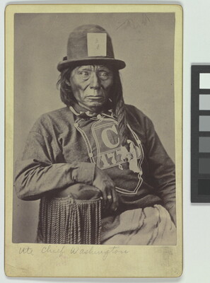 A black-and-white portrait photograph of a seated Indigenous man wearing a long-sleeved t-shirt and bowler hat.