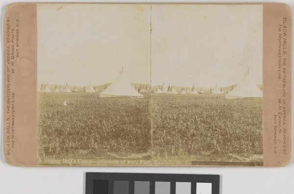 A sepia-toned stereograph of multiple tipis on a grassy field.