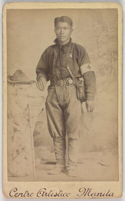A black-and-white photograph of a medium-skinned soldier with a canteen slung across his chest and wearing a Red Cross armband.