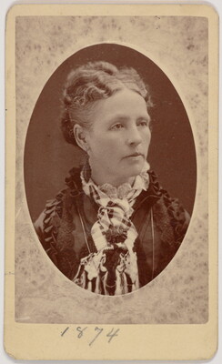 A black-and-white oval-shaped portrait photograph of a White woman, hair pulled up, wearing a dress with a high ruffled neck.