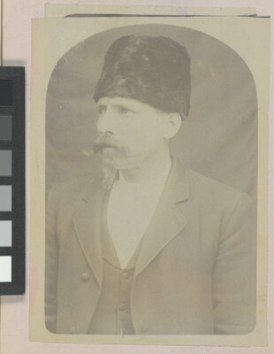 A faded sepia-toned portrait of a White man with a handlebar moustache wearing a fur Cossack-stye hat and a three-piece suit.