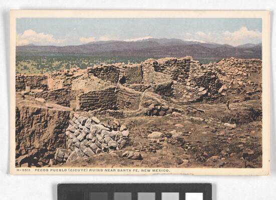A color postcard of a ruined, stone building with multiple rooms in a mountainous landscape.