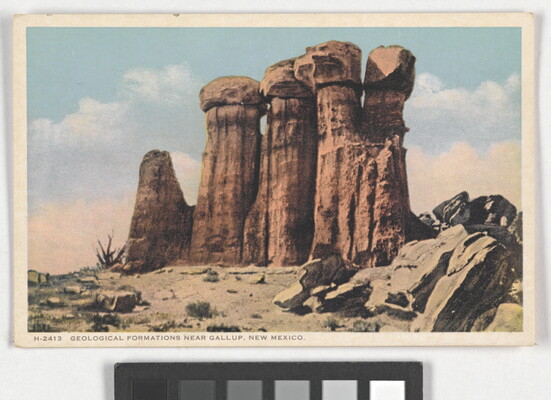 A color postcard of a tall rock formation in a desert landscape.