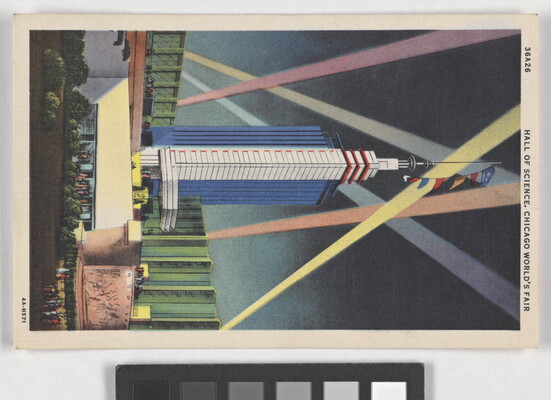 A color postcard of a tall, modern skyscraper illuminated by beams of light.