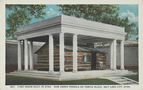 A color postcard of a log cabin covered by a columned structure.
