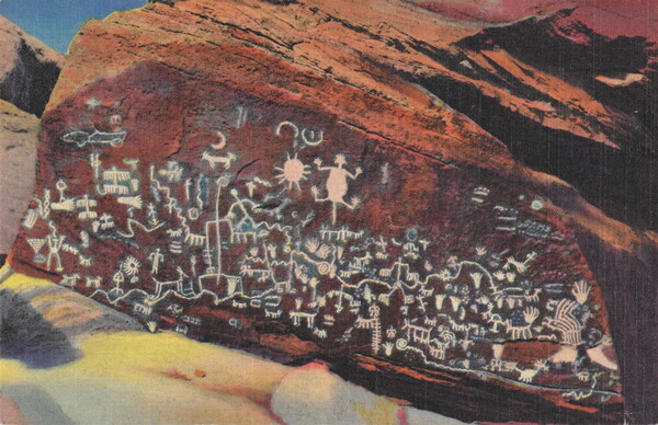 A color photograph on a postcard of Native American pictographs in white on a large red rock.