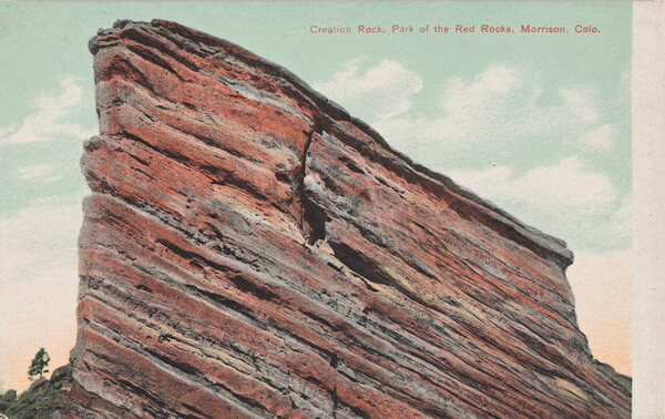 A color postcard of a tall, red rock formation jutting into the sky.