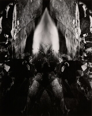An abstract black-and-white photograph of rock formations, waterfalls, and other natural materials reflected to create a symmetrical design.