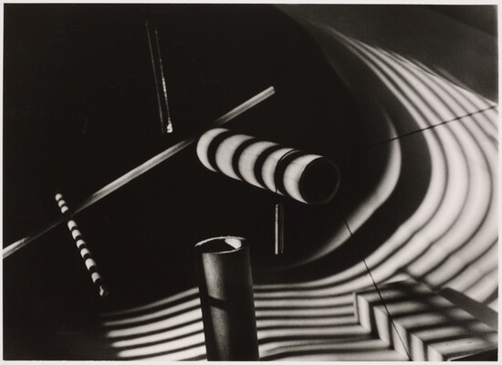 An abstract black-and-white still life of several dowels with striped shadows cast over them.