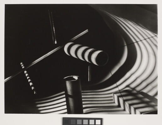 An abstract black-and-white still life of several dowels with striped shadows cast over them.