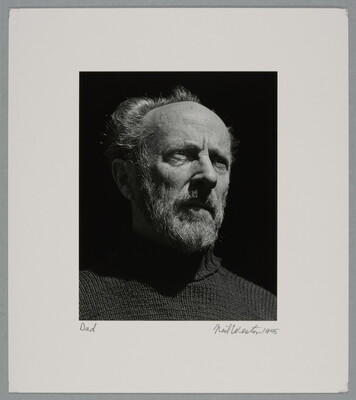 A black-and-white portrait photograph of an older, bearded White man wearing a turtleneck looking out into the distance.