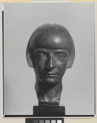A black-and-white photograph of a bronze bust of a woman with a bobbed haircut from the front.