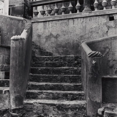 A black-and-white photograph of a decorative stone staircase that is starting to crumble.
