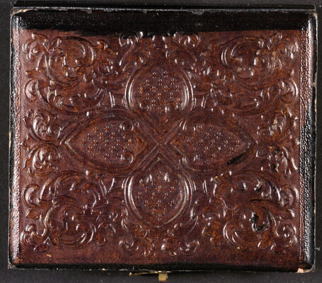 The cover of a photograph case showing an embossed design.