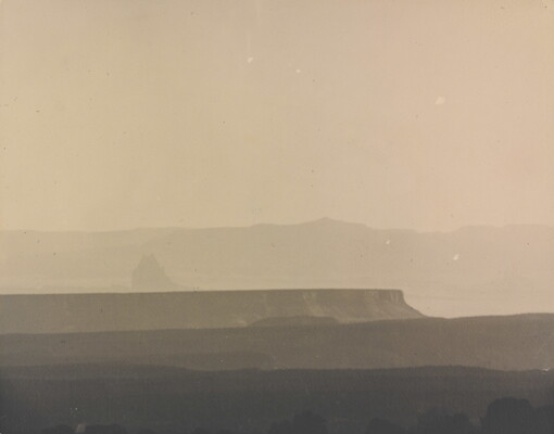 A sepia-toned photograph of a hazy mesa and distant mountains.