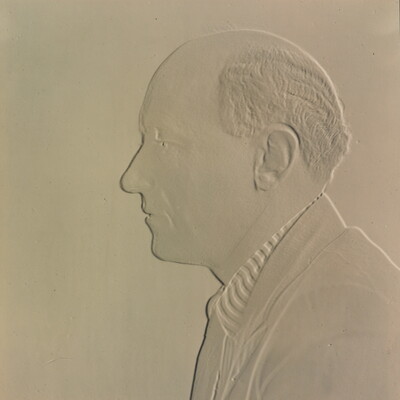 A white embossed photograph of a balding White man in profile.