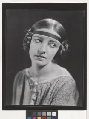 A black-and-white portrait of a White woman, eyes looking to the side, with her hair braided into buns on the sides of her head.