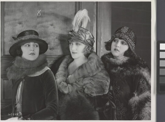 A black-and-white photograph of three elaborately-dressed White women, all wearing hats and fur stoles.