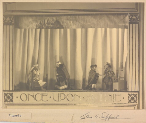 A sepia-toned photograph of a puppet stage with four puppets and the words "Once Upon a Time" written at the bottom.