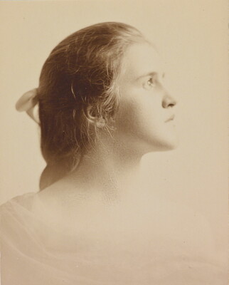 A black-and-white portrait photograph of a White woman in profile, hair pulled back with a bow.