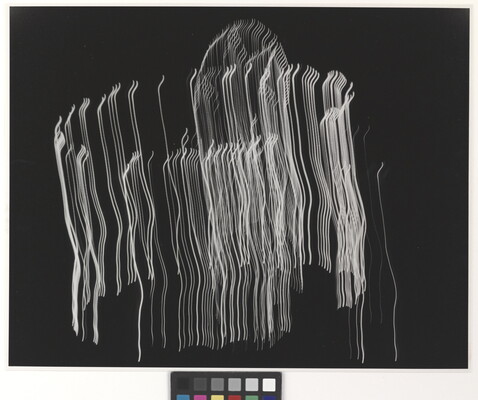 A black-and-white photograph of vertical streaks of white light layered in a circular shape on a black background.