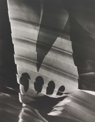 An abstract black-and-white photograph of a skewed white rectangular shape broken by a dark triangle, four tear-drop shapes, and lines.