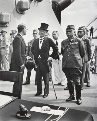 A black-and-white photograph of a group of Asian men standing at attention; most are in military uniforms and one is wearing a tuxedo and top hat.