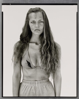 A black-and-white portrait photograph of a White woman with long hair, wearing a bikini top and athletic shorts.