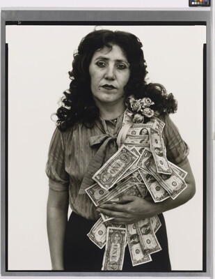 A black-and-white portrait photograph of a White woman with a sash of flowers and dollar bills flowing over her shoulder.
