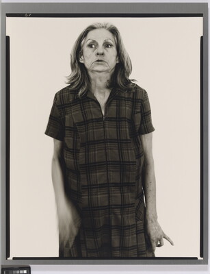 A black-and-white portrait photograph of an older White woman with medium-length gray hair, head held back slightly, wearing a house dress.