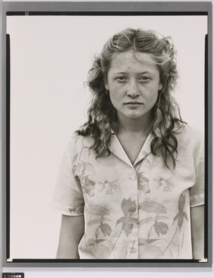A black-and-white portrait photograph of a White teenage girl with her blonde hair pulled back in barrettes and wearing a floral button-up blouse.