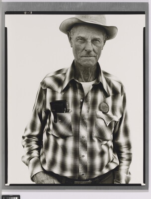 A black-and-white portrait photograph of an older White man wearing a plaid, button-down shirt and western hat.