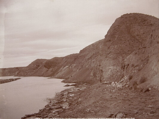 A black-and-white photograph of a river lined with tall rock formations.