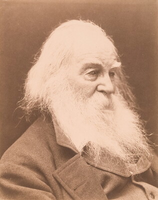 A black-and-white portrait photograph of an elderly White man in three-quarter view with a long white beard wearing an overcoat.