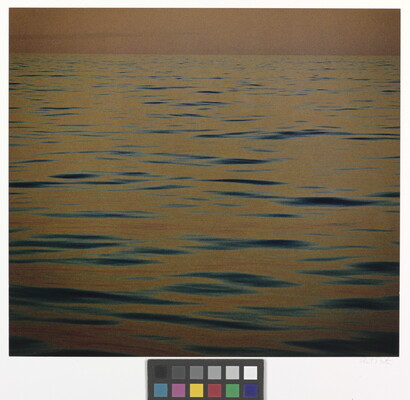 A color photograph of calm ripples of the sea at sunset reflecting an orange-red sky.